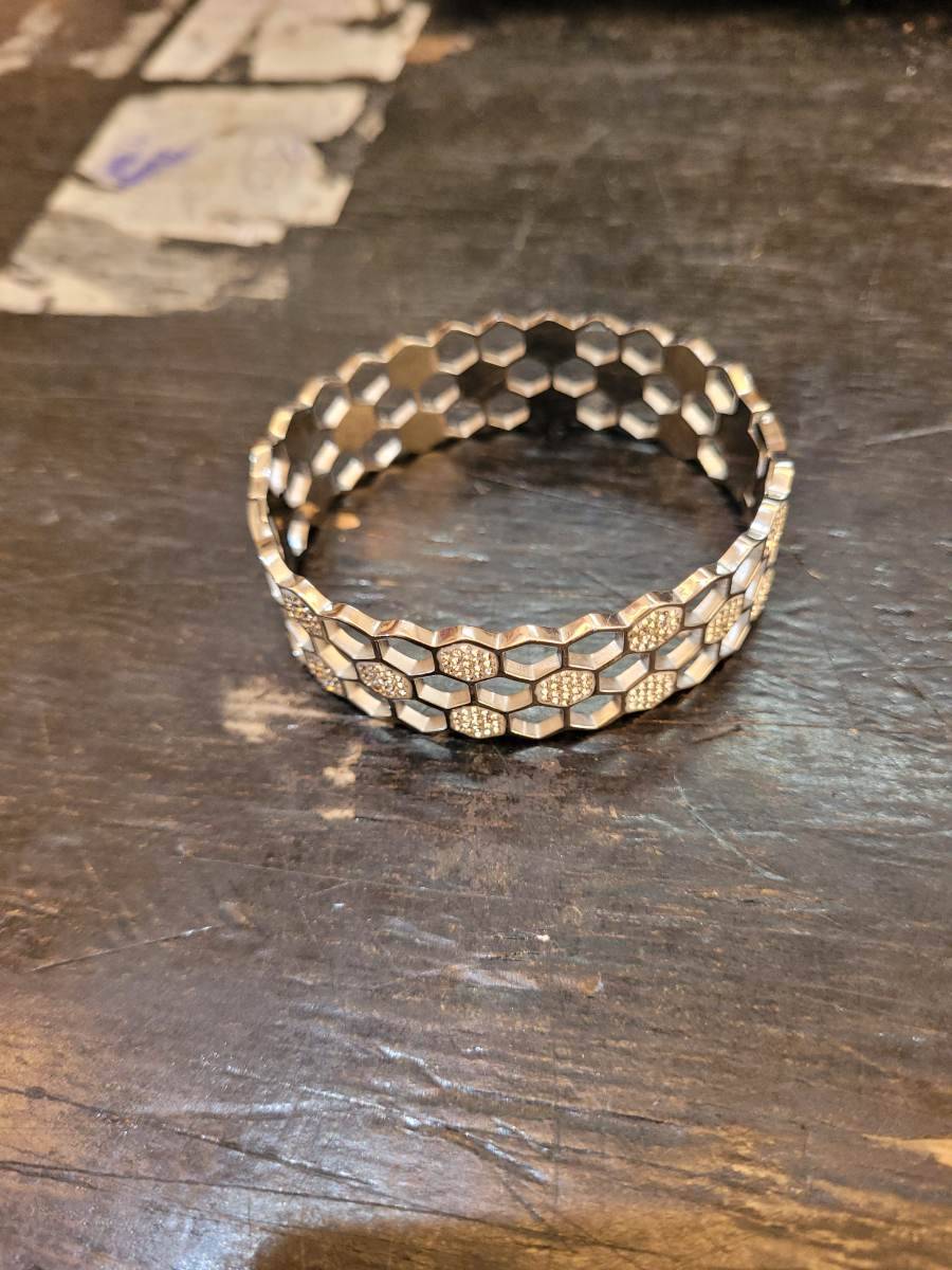 Pulseira metálica com design hexagonal e detalhes brilhantes
