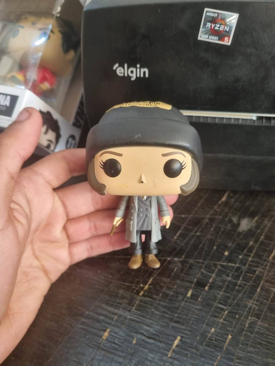 Boneco Funko Pop feminino com casaco cinza e chapéu preto