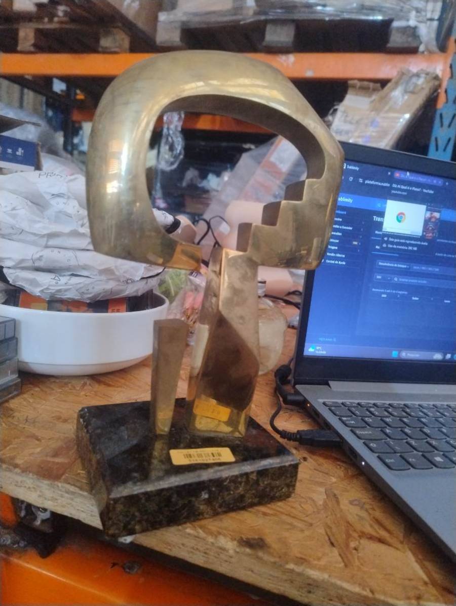 Escultura decorativa abstrata em metal dourado com base de pedra
