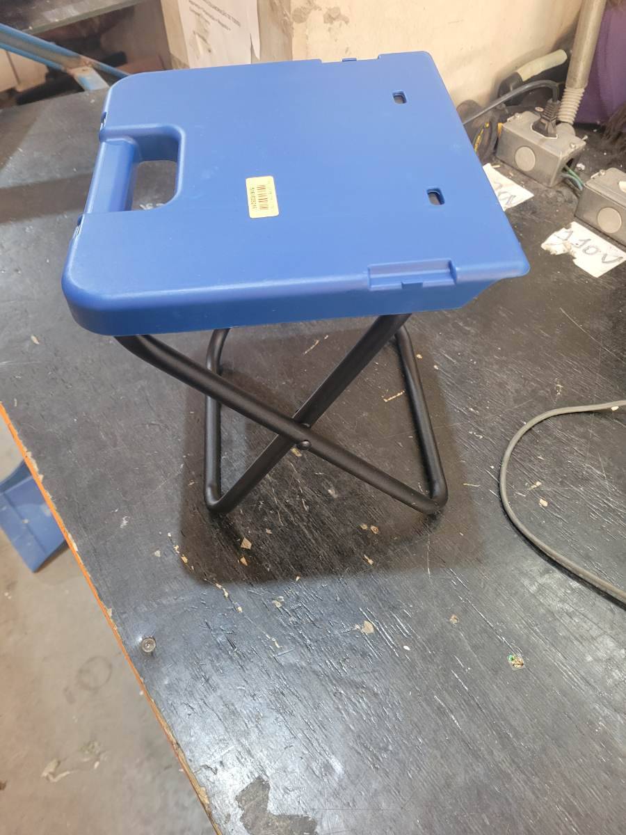Banqueta dobrável com assento plástico azul e estrutura metálica preta